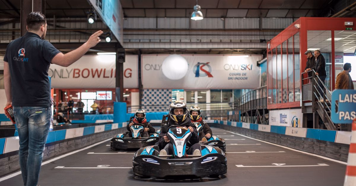 Mehrere Fahrer starten mit Karts auf einer Indoor-Rennbahn