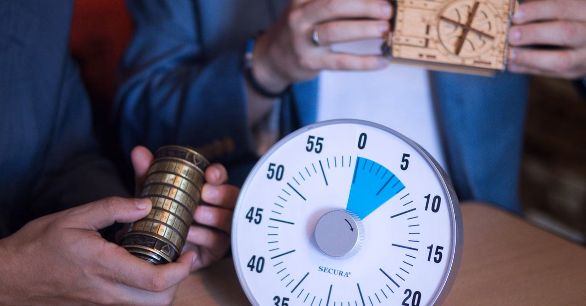 Zwei Personen halten Rätselschlösser vor einem grossen Timer