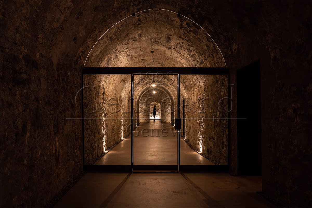 Beleuchteter Gewölbekeller der La Corne à Vin mit Blick durch eine Glastür