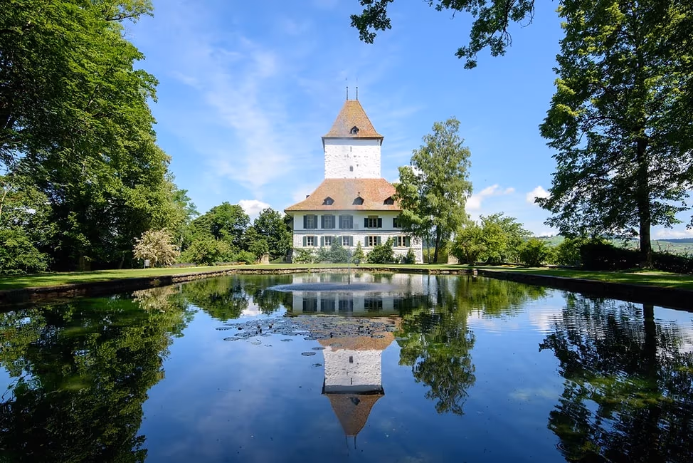 Schloss Wyl spiegelt sich im Teich des Schlossparks.