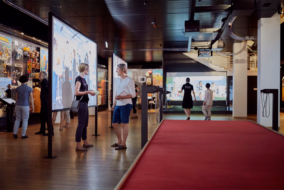 Ausstellung im Museum für Kommunikation mit rotem Teppich und Videoprojektionen