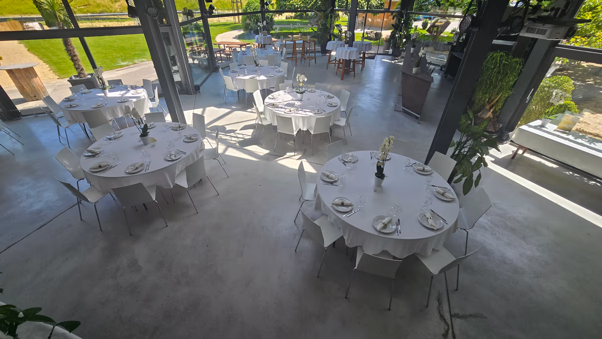 Lichtdurchfluteter Wintergarten von LF22 mit gedeckten runden Tischen